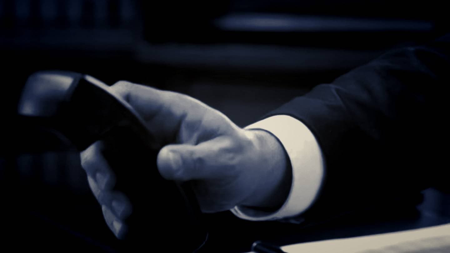Reaching for the office phone — graded still from the firm film